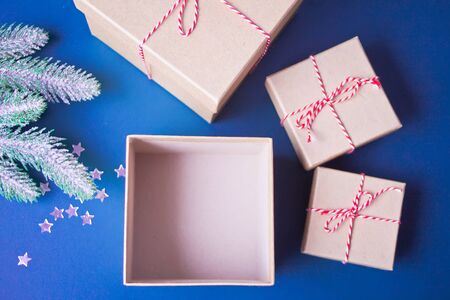 Opening and empty Christmas gift boxes on the blue background with pine branch and Christmas...