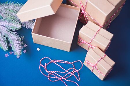 Opening and empty Christmas gift boxes on the blue background with pine branch and Christmas...
