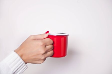 Woman's hand holding red mug on the white background.の写真素材