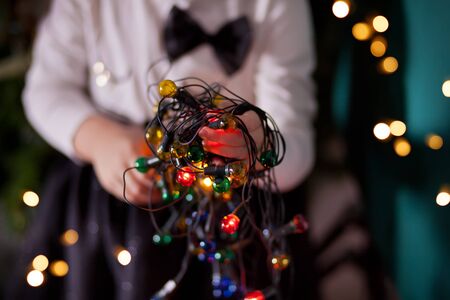 The girl is holding a Christmas garland in her hands. Warm Christmas mood.