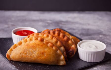 Fied meat pies empanadas cheburek with dips on the black plate