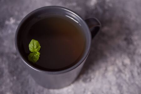Gray mug of mint tea on dark stone background. Top view.の写真素材