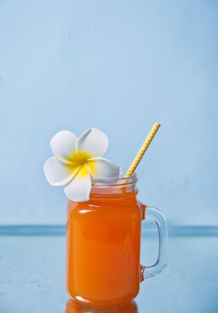 Glass of tropical exotic multifruit juice cocktail drink with Plumeria frangipani flower for decorationの写真素材