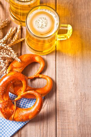 Freshly baked homemade salt Bavarian pretzel with rwo glass of beer on the wooden table. Top view. Copy space.の写真素材
