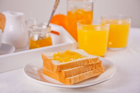 Bread toast with orange jam, glasses of orange juice on the white background. Breakfast concept