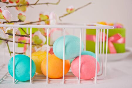 Colorful eggs for Easter day and small cakes on the background