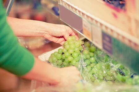 Young woman buying green grape in a supermarketの写真素材