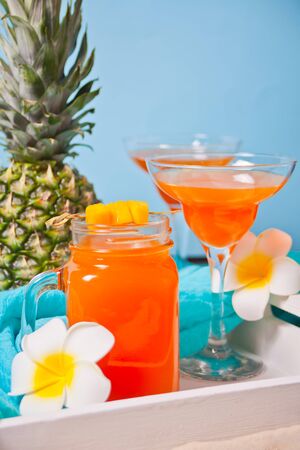Glasses of tropical exotic multifruit juice on the wooden white tray with fruits on the backgroundの写真素材