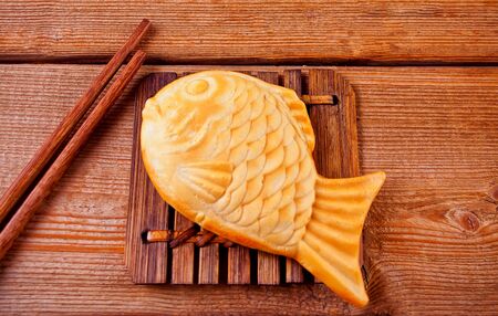 Taiyaki Japanese street food fish-shaped sweet waffle on wooden tableの写真素材
