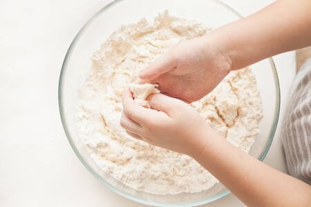 Little child in the home kitchen preparing dough for pizza or another food. Top view