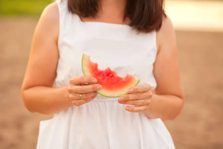 Woman with a piece of ripe watermelon in a hand in a picnic. Summer picnic. Vacation conceptの写真素材