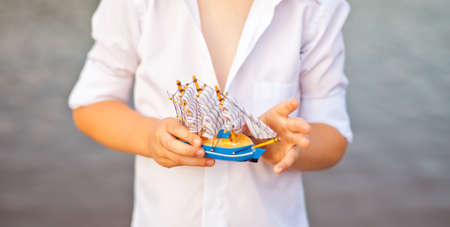 Boy holding toy boat, model of the ship.の写真素材