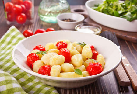 Homemade Italian gnocchi with tomato cherry on the wooden tableの写真素材