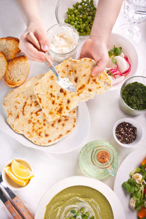 Homemade Indian naan flatbread with fresh salad and dips on the dinner table.の写真素材