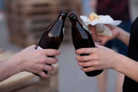 beer bottles raised for a toast. Hands of women clinking bottles.の写真素材