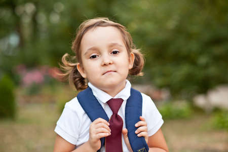 little cute schoolgirl in uniform with school bag backpackの写真素材
