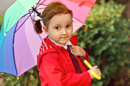 Little child with multicolored rainbow umbrella outdoorsの写真素材