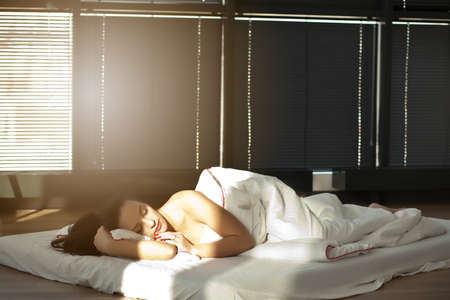 A brunette woman lying on the bed at home and sleeping.