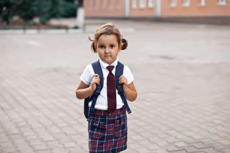 little cute schoolgirl in uniform with school bag backpackの写真素材