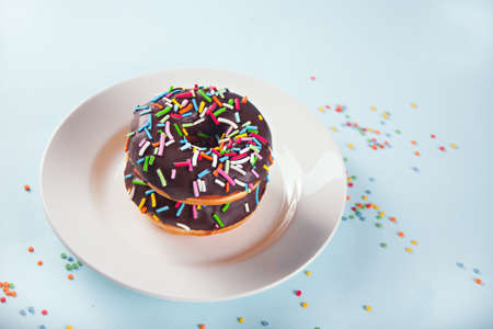 Delicious donuts chocolate icing with colorful edible confetti on the plate. Birthday concept.