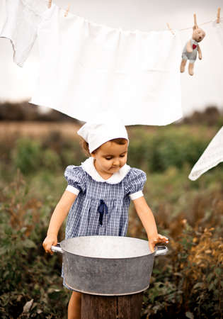 Baby girl washing dolls in a tin basin. Retro style.の写真素材