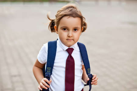 little cute schoolgirl in uniform with school bag backpackの写真素材