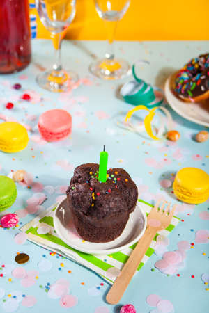 Delicious chocolate muffin cupcake with Birthday candle and other sweets and candies on the background. Party conceptの写真素材
