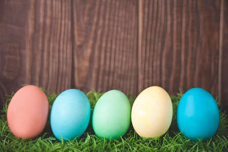 Colorful Easter eggs in the grass on wooden background.の写真素材