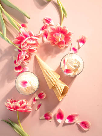 Ice cream cone and sundae with pink flowers and petals. Summer concept. Flat lay.