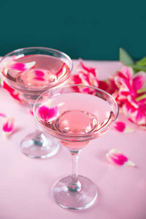 Glasses of pink cocktail with flowers and petals. Birthday party or Valentines day romatic couple concept.の写真素材