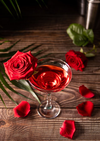 Delicious refreshing beverage drink red cocktail with red rose and petals on wooden table. Romantic, Valentines day concept.の写真素材