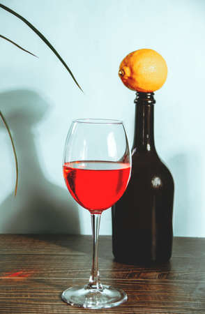 Glass of red wine with bottle and lemon on the backgroundの写真素材