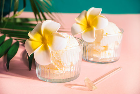 Delicious tropical flavors ice cream sorbet sundae decorated with flower plumeria frangipani and palm leaf on the background . summer food conceptの写真素材