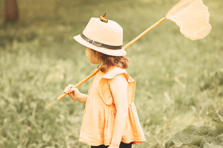 Girl with butterfly net having fun at field. Child catching butterflies and exploring nature. summer conceptの写真素材