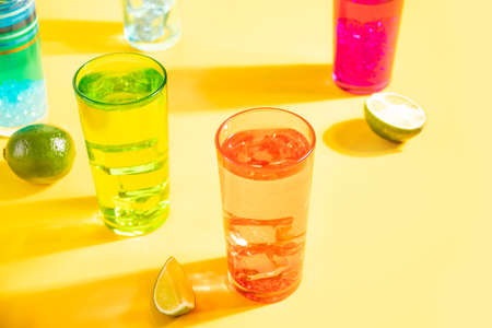Summer alcoholic cocktails in colorful glasses on yellow background. Summer sea ocean vacation and travel conceptの写真素材