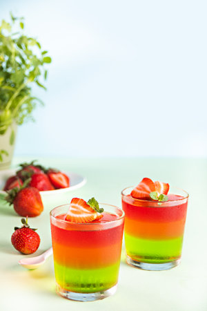 Glasses of tasty summer dessert layered colorful jelly with fresh strawberries.の写真素材