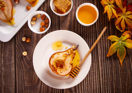 Honey or maple syrup roast pears with walnuts on wooden background. Vegetarian diet health delicious dessert. top view.の写真素材