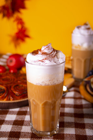 Pumpkin spice whipped latte in glass. Hot autumn beverage. Nearby delicious pie and appetizers fruits and cheeseの写真素材