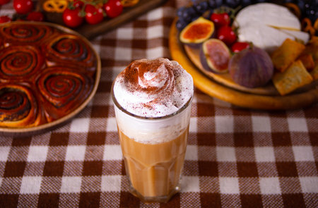 Pumpkin spice whipped latte in glass. Hot autumn beverage. Nearby delicious pie and appetizers fruits and cheeseの写真素材