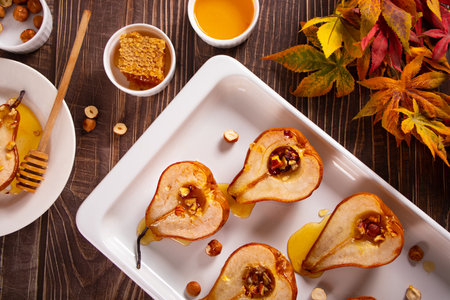 Honey or maple syrup roast pears with walnuts on wooden background. Vegetarian diet health delicious dessert. top view.の写真素材
