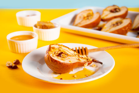 Honey or marple syrup roast pears with walnuts on yellow background. Vegetarian diet health delicious dessertの写真素材