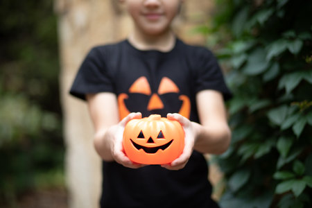 Cute kid boy in jack-o-lantern pumpkin t-shirt holding lantern in Halloween holidayの写真素材