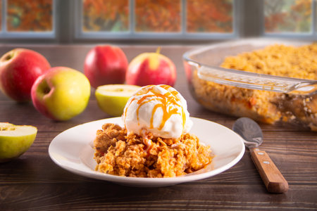 Homemade apple cramble crisp cake on white plate with autumn leaves on the background.の写真素材