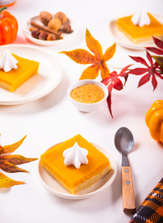 Slice of fresh baked traditional american homemade pumpkin pie cut into square pieces decorating whipped cream for celebrating holidaysの写真素材