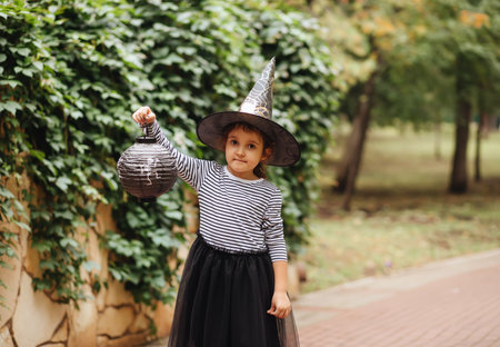 Little cute girl in witch costume holding paper lantern. Kid having fun on Halloween holidayの写真素材