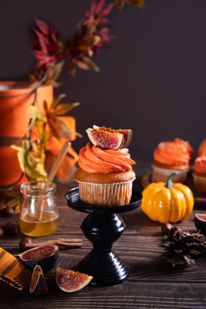 Delicious homemade autumn season spicy pumpkin cupcakes with whipped orange cream with fruit figsの写真素材