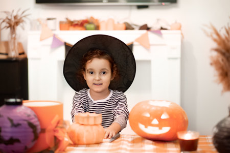 Girl kid child carving traditional Halloween jack-o-lanterns with scary face for party at home.の写真素材
