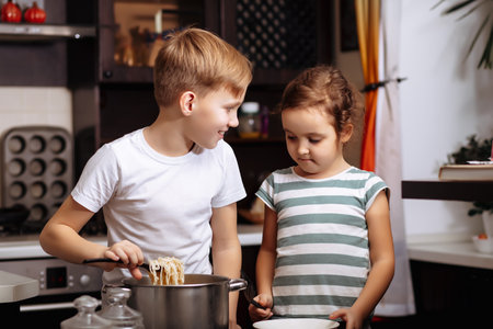 Teenage Boy and little girl in the kitchen at home making dough for pancakes pastry. Children cooking concept.の写真素材
