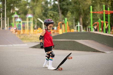 Cute kid girl child with skateboard in a hands standing in a skatepark and smiling. Child performs tricks. Summer sport activity concept. happy childhood.の素材 [FY310210186833]