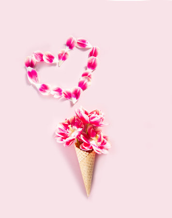 Ice cream cone with pink flowers and petals. Valentines day concept. flat layの写真素材